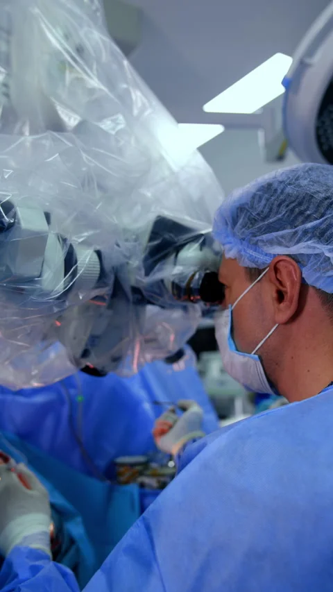 Doctor looking at microscope and using a tool talks to his colleagues Vidéo 271303559