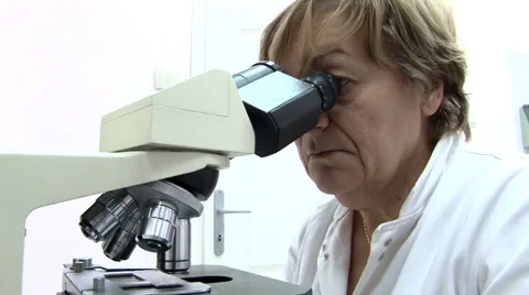Doctor looking into a microscope in the lab Видео 35768113