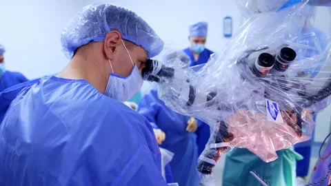 Doctor looks attentively into microscope at operation. Stock Footage 307941123