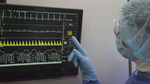 The doctor looks at the readings of a medical device monitor Stock Footage