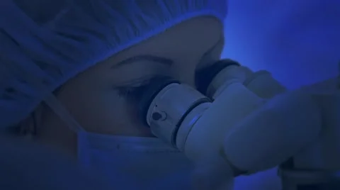 Doctor looks through a microscope during surgery, microsurgery, CINEMATIC BLUE Stock Footage 51445693