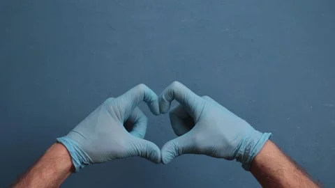 Doctor's hands in medical gloves in shape of heart on blue