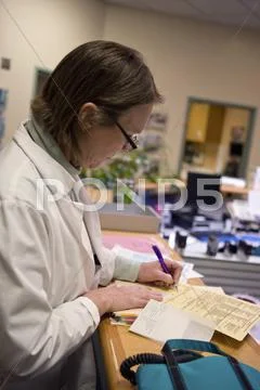 A doctor making notes on a medical chart Stock Photos