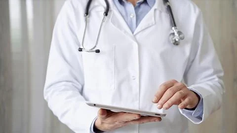 Doctor man with stethoscope using tablet computer in hospital. Medicine and Stock Photos