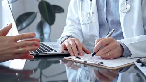 Doctor man is writing something while consulting patient on the glass desk and a Stock Photos