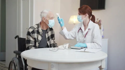 A doctor measures the temperature of an elderly disabled person using an Stock Footage 173482453