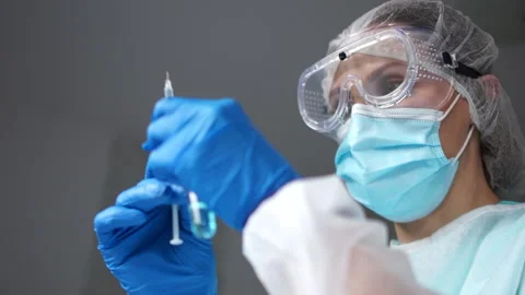 Doctor in medical mask holds in hand ampoule and syringe with vaccine against Stock Footage