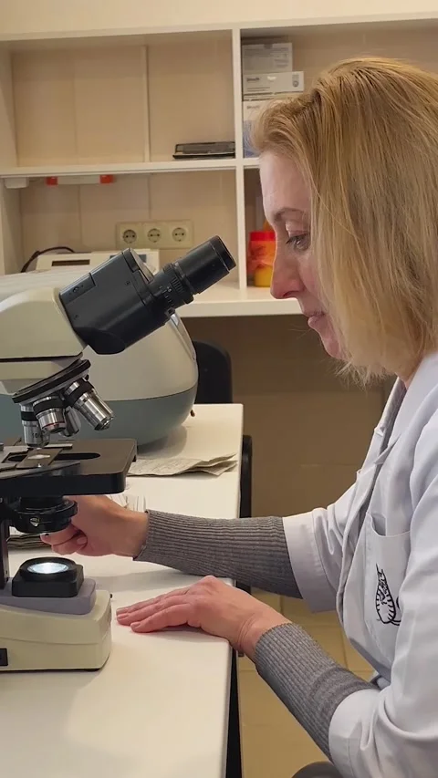 A doctor at a microscope in a laboratory writes the result of the analysis on a Video stock 312140907