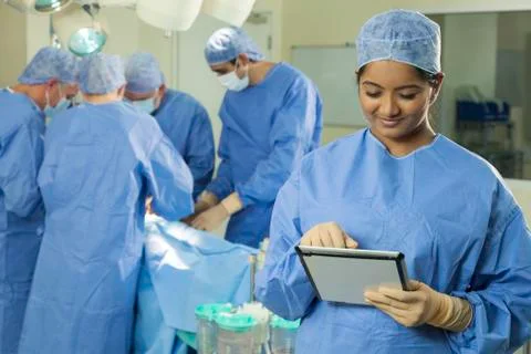Doctor nurse using tablet computer &amp; surgical team Stock Photos