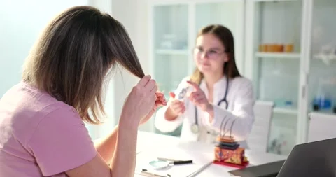 Doctor offers cure for split ends to female patient in clinic Stock Footage 237175692