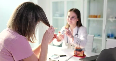 Doctor offers cure for split ends to female patient in clinic Stock Footage 263958592