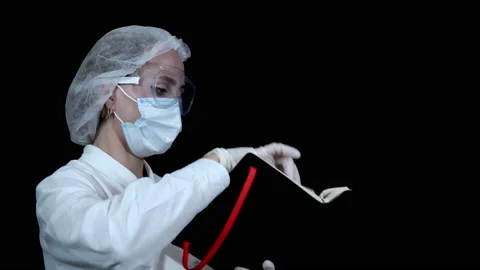The doctor opens a work notebook, leafs through and looks for some kind of entry Stock Footage 141316356