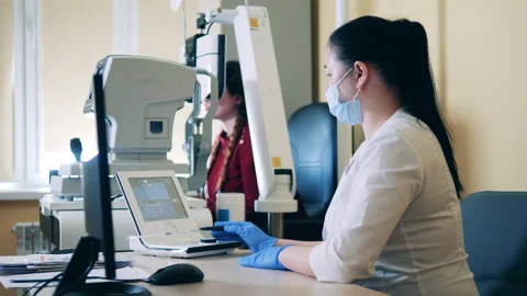Doctor is operating computerized machine to check lady's eyes Video stock 151744925