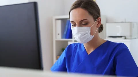 Doctor or nurse in mask with computer at hospital Stock Footage