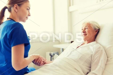Doctor or nurse visiting senior woman at hospital Stock Photos