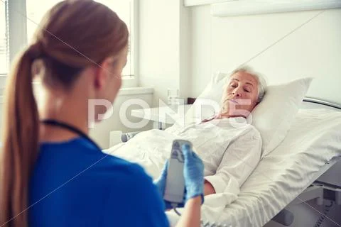 Doctor or nurse visiting senior woman at hospital Stock Photos