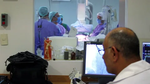 Doctor outside operating room looking a monitor, back surgeons during surgery. Stock Footage 48469796