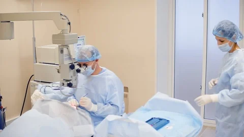 Doctor performs cataract treatment of the eye, nurse helps the ophthalmologist Stock Footage