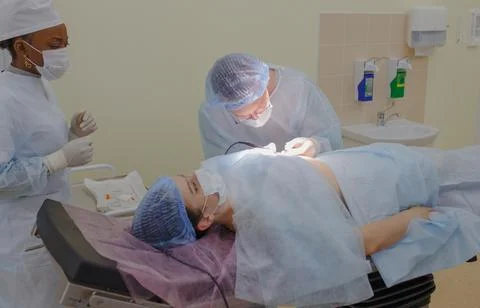 The doctor performs the operation on the patient lying on the operating table Stock Photos