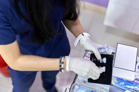 Doctor picking up two bottles of solution from a box for a facial treatment Stock Photos