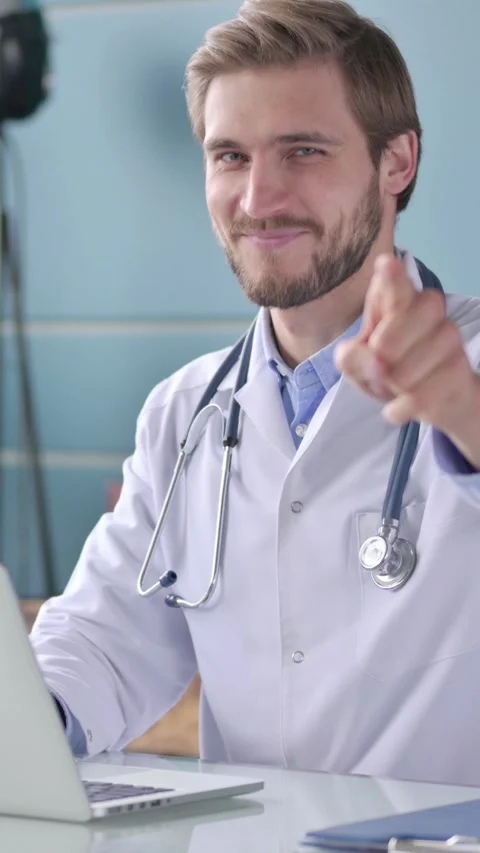 Doctor Pointing at Camera while using Laptop in Office, Vertical Video 動画素材 339580258