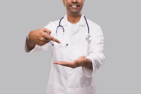 Doctor Pointing at Empty Open Hand in front of Chest Close Up Isolated. Indian Foto stock