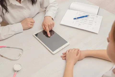 Doctor pointing at tablet screen during medical consultation representing d.. Stock Photos