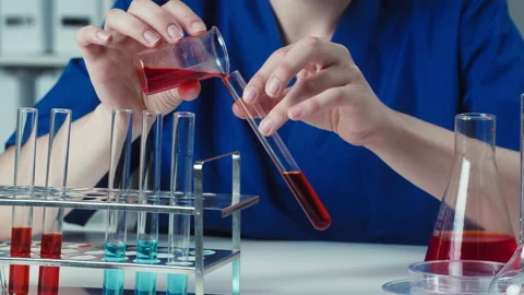 Doctor pouring red solution into flask close-up. Young chemist working in modern Stock Footage 156752214