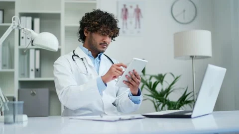 A doctor practitioner uses the digital tablet phone working while sitting  Stock Footage 235478587