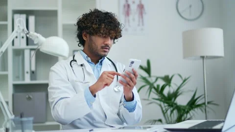 A doctor practitioner uses the phone working while sitting in a modern office  Stock Footage 235479364