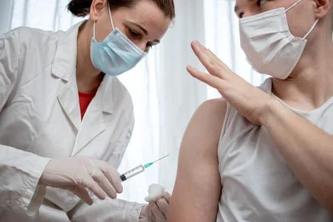 Doctor preparing to inject a worried male patient with antiviral vaccine. Stock Photos