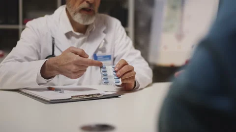 Doctor prescribes medication for prostate condition to patient during check-up Stock Footage 342749686