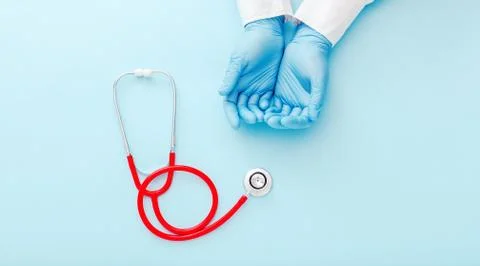 Doctor presenting empty hands, blank palm and red stethoscope on blue color b Stock Photos