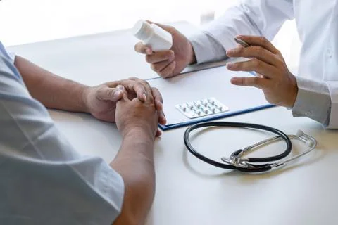 Doctor presenting with patient and checking results on report and prescriptio Stock Photos
