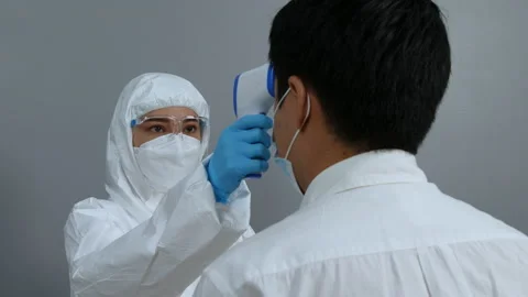 Doctor in protective PPE suit using infrared thermometer  Stock Footage 166906747