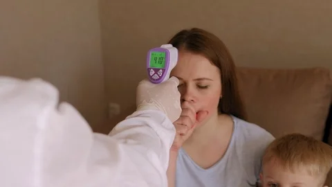 Doctor in a protective suit measures the temperature of a woman with coronavirus Stock Footage 130136696