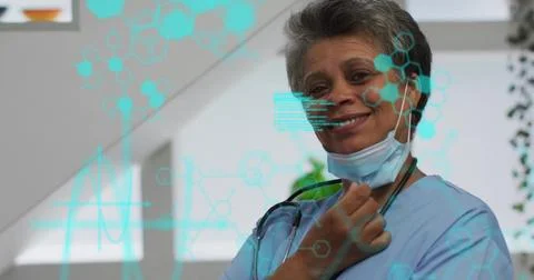 Doctor pulling mask down and smiling in clinic with stethoscope and data Stock Photos