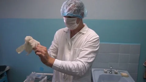 The doctor puts on rubber gloves before taking the patient Video stock 77199109