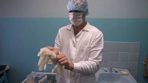 The doctor puts on rubber gloves before taking the patient Stock Footage 77199763