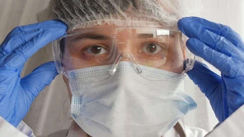 Doctor putting on protective goggles, looking at camera, portrait Video stock 126838992