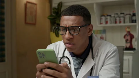 Doctor reads bad news using mobile phone. Upset African American man is nervous Stock Footage 220563045
