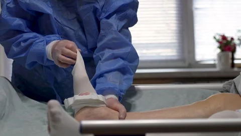 Doctor Removing Medical Compression Stocking from Patient. Healthcare profe.. Stock Footage 329907903