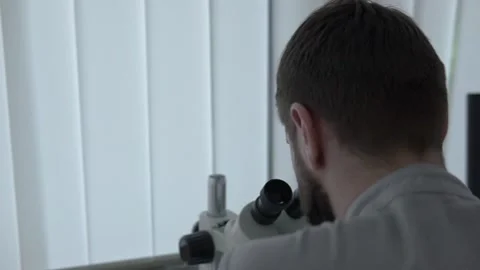 Doctor scientist is looking at microscope 動画素材 130980302