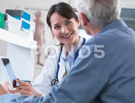 Doctor Sharing Health Information On Digital Tablet With Patient In Clinic