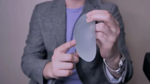 Doctor showing difference in sizes and shapes of breast implants Video stock 150803074