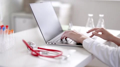 Doctor sitting at the table and typing on laptop. Stock Footage 260233309