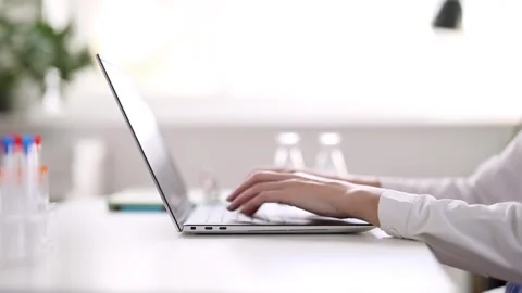 Doctor sitting at the table and typing on laptop. Stock Footage 260233325