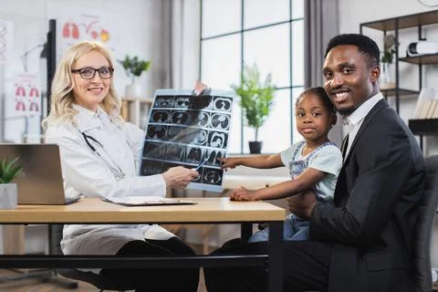 Doctor smiling at camera while explaining little girl's x-ray scan to handsome Foto stock