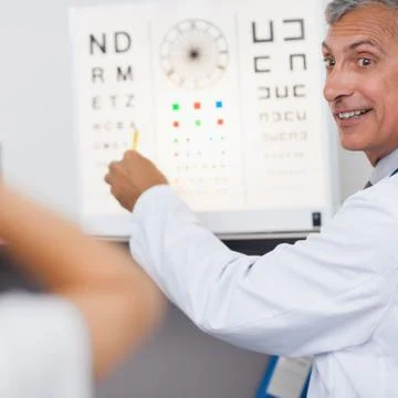 Doctor smiling while doing an eye test on a patient in a hospital Stock Photos