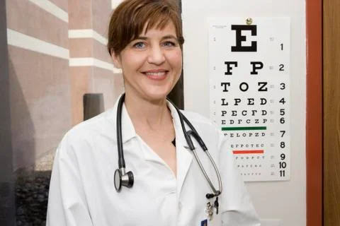 A doctor standing in front of an eye chart, smiling Stock Photos